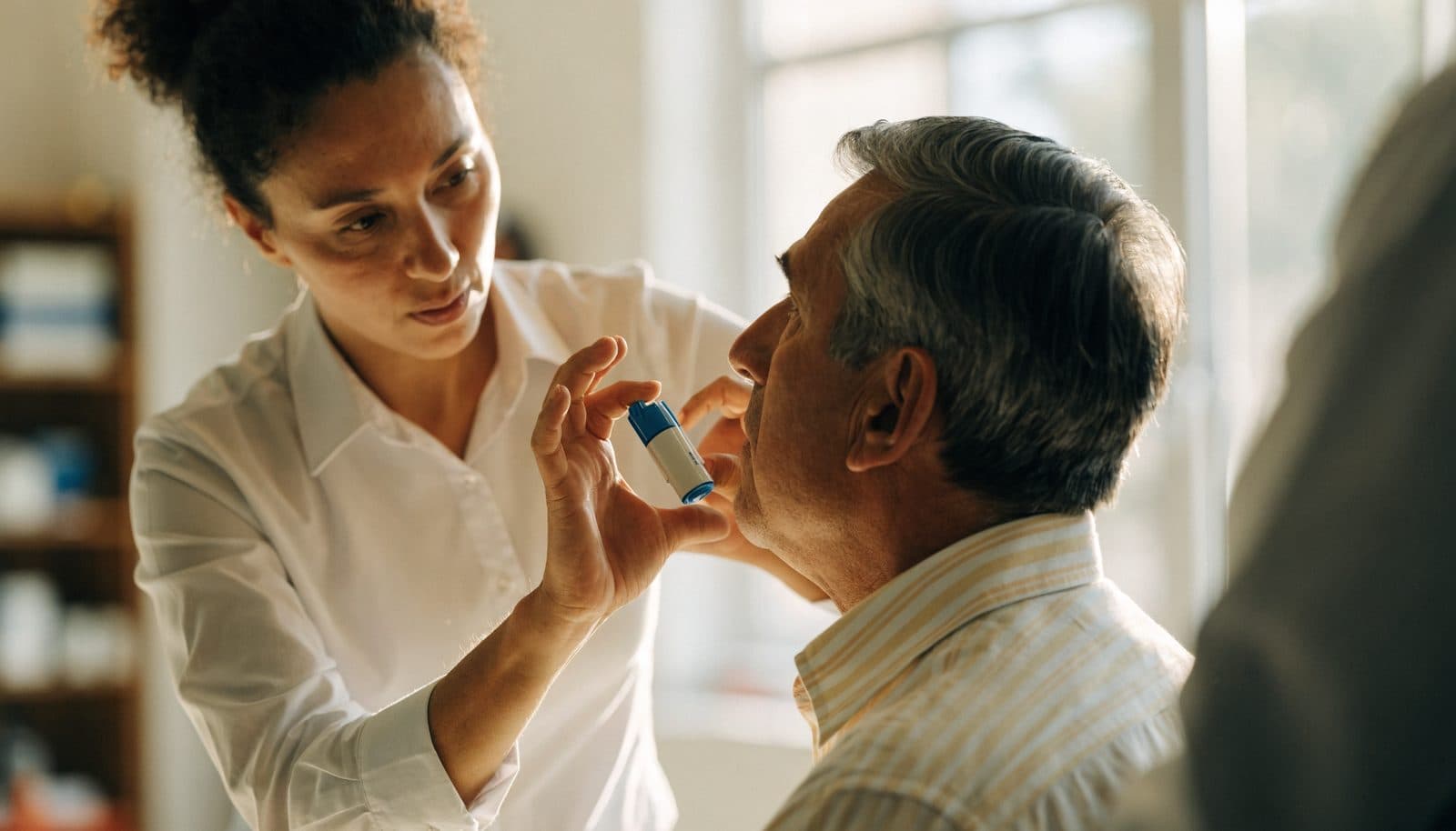 A respiratory therapist coaching a patient on inhaler technique